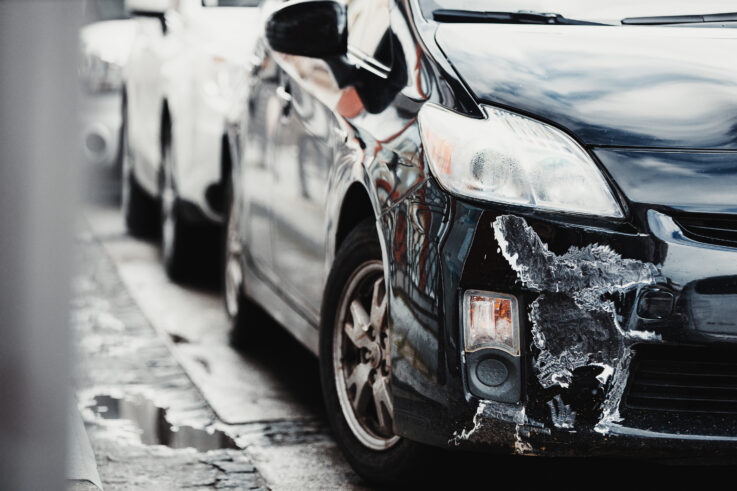 Car with broken, scratched, and dented bumper and fender after collision