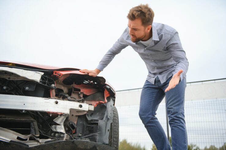 Damaged Car with Driver Looking On in Despair