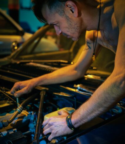 Automotive technician performing repairs near the engine