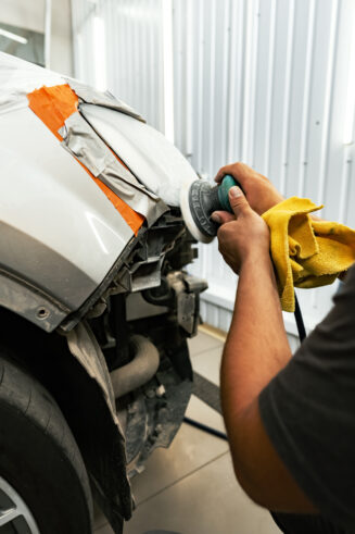 Close up of car cleaner polishing headlight with polish machine