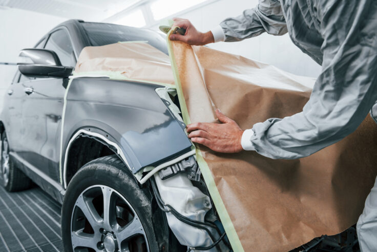 Caucasian automobile repairman in uniform working in garage