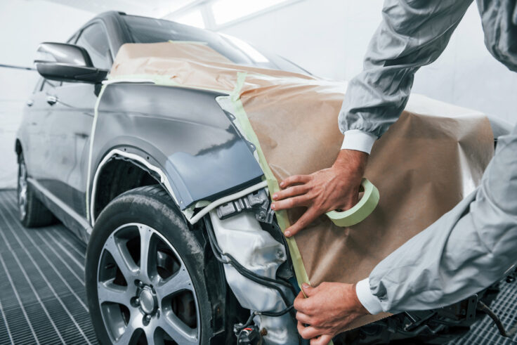 Caucasian automobile repairman in uniform working in garage