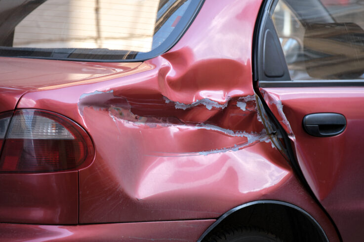 Dented car with damaged body parked on city street side