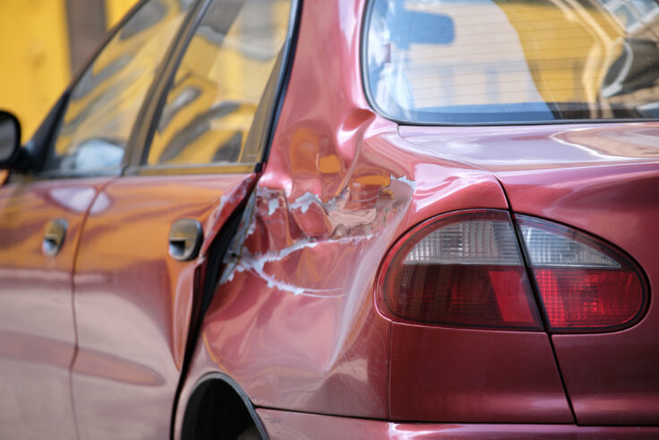 Dented car with damaged body parked on city street side