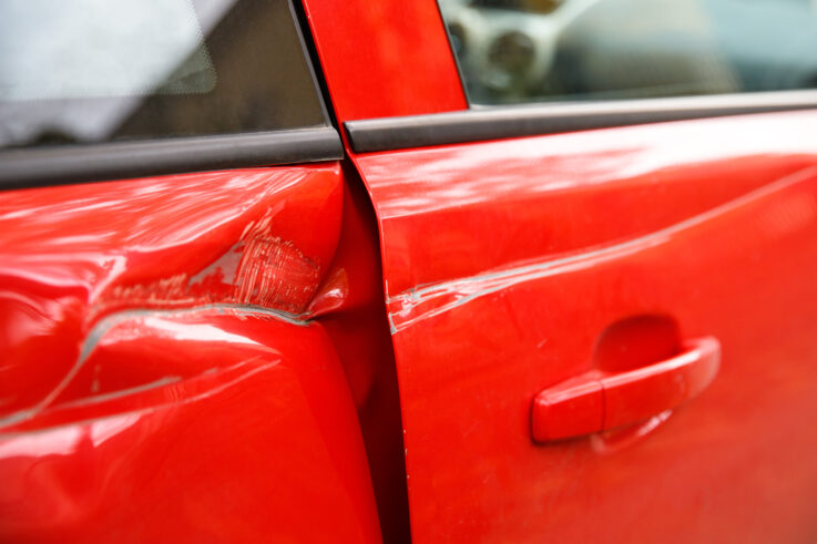 Red Car with Deep Dent in Door After Accident