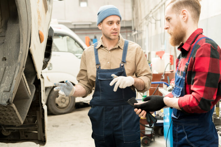 Mechanics discussing truck breakdown in a garage