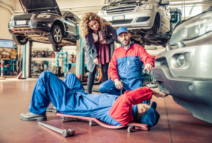 Mechanics working on damaged car in repair shop