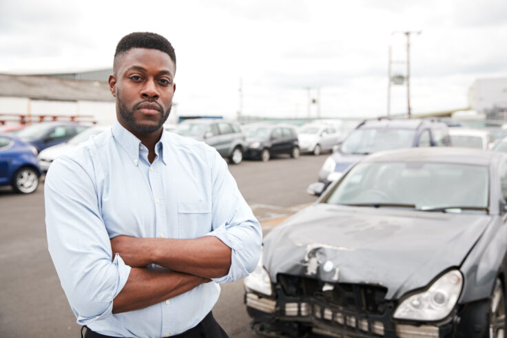 Motorist standing next to damaged car after a motor accident