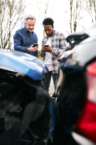 Two male drivers exchanging car insurance details after road traffic accident