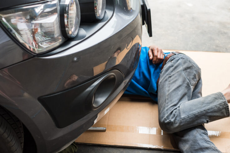 Mechanics under car performing engine oil change